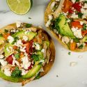 Chicken tostadas with refried beans, chicken, lettuce, salsa, cheese, and cilantro.