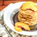 Low carb coconut pancakes on a plate with sliced peaches.