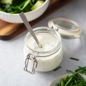 Creamy gorgonzola dressing with chunks of gorgonzola cheese, Greek yogurt, chives, and buttermilk in a small glass jar.