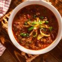 Easy beef chili in a bowl with shredded cheese, green onions, and beans,