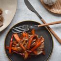 Pepper steak with thinly sliced sirloin steak, bell peppers, onions, and a peppery stir fry sauce on a plate with rice. 