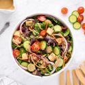 Spring mix salad in a bowl with various lettuce, cucumbers, tomatoes, and balsamic dressing.