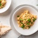 Garlic parmesan cauliflower rice with fresh parsley in a bowl with a wooden fork. 