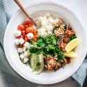 Greek groudn turkey served in a bowl with cherry tomatoes, feta cheese, cucumbers, and fresh herbs. 