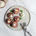 Grilled plums on a plate with honey, butter, cinnamon, and a dollop of whipped cream.