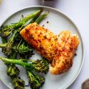 Grilled red snapper with homemade spice rub on a plate with grilled broccoli.