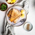 Grilled swordfish with garlic, lemon, and herbs on a plate with fresh parsley.