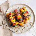 Grilled vegetable skewers with red onion, bell pepper, zucchini, summer squash, and mushrooms on wooden skewers.