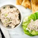 Healthy tuna salad with celery in a bowl with lettuce and pita triangles on the side.