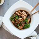 Honey mustard chicken with broccolini in a white bowl with a honey balsamic sauce poured on top.