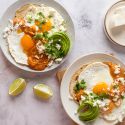 Huevos rancheros with sunny side up eggs served on corn tortillas with ranchero sauce, avocado, and cheese.