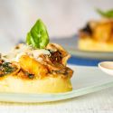 Baked polenta with tomato sauce, vegetables, and cheese with fresh basil.