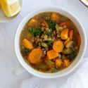 Lentil soup with cooked green lentils, carrots, onions, and celery served in a bowl with herbs,