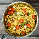 Caprese pasta in a pot with cherry tomatoes, mozzarella cheese, and basil.