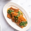 Pan seared cod with a crispy seasoned flour crust on a white plate with lemon garlic sauce.