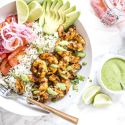 Shrimp rice bowls with grilled shrimp, white rice, cilantro mint sauce, salsa criolla, and sliced avocado.