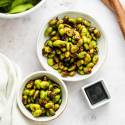 Sauted shelled edamame with caramelized edges served with soy sauce and chili flakes.