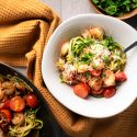 Healthy shrimp scampi zoodles with garlicky shrimp, tomatoes, Parmesan cheese, zucchini noodles, and parsley in a bowl.