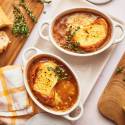 Slow Cooker French Onion soup in a bowl with bread and melted cheese.