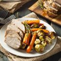 Slow Cooker Maple Pork Tenderloin sliced on a plate with carrots and Brussels sprouts.