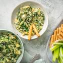 Slow cooker spinach artichoke dip with kale in three bowls with celery and breadsticks.