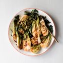 Stir fried bok choy on a plate with red onions, soy sauce, coconut oil, and chili paste.