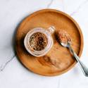 Homemade taco seasoning in a small jar with a spoon including chili powder, oregano, paprika, cumin, and other spices. 