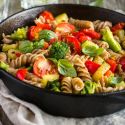 Vegetable scampi in a bowl with broccoli, tomatoes, zucchini, and a garlic butter sauce. 