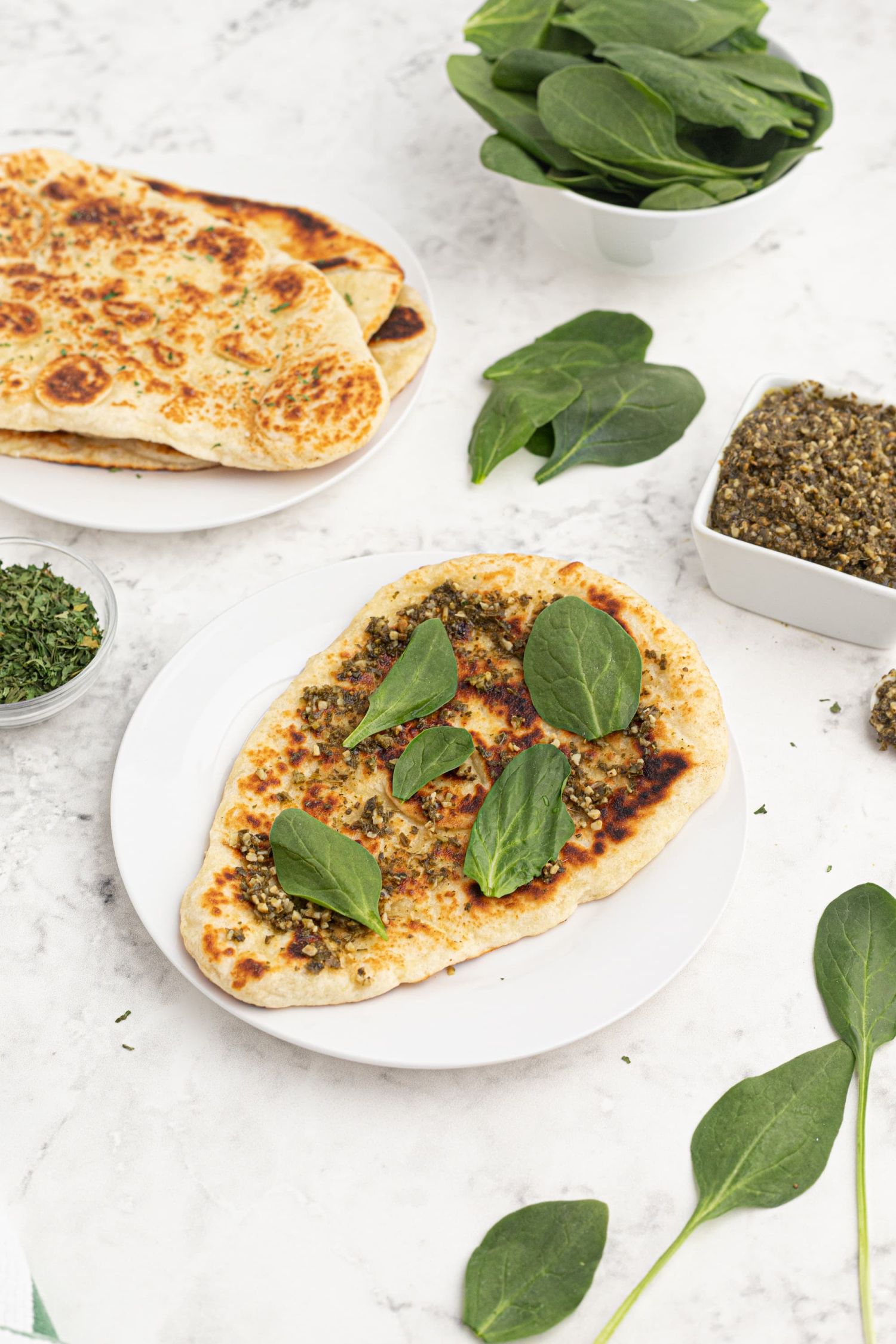 Naan bread with a spicy Indian chutney and fresh spinach on top served with extra Naan and spices on the side.