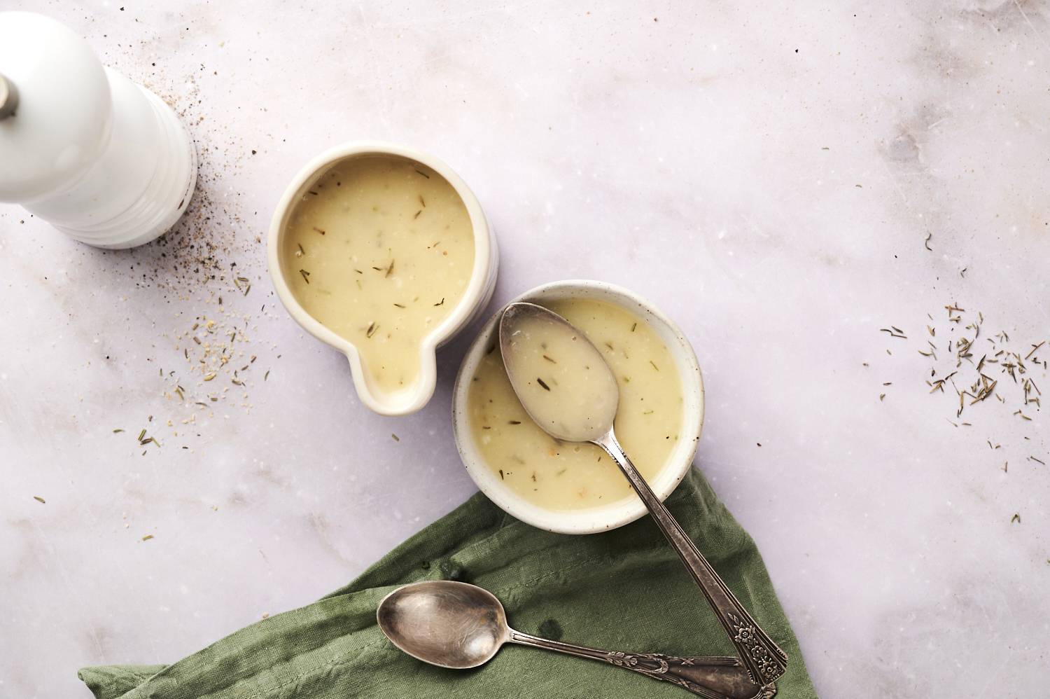 Gravy in two bowls, with a spoon in one of them.