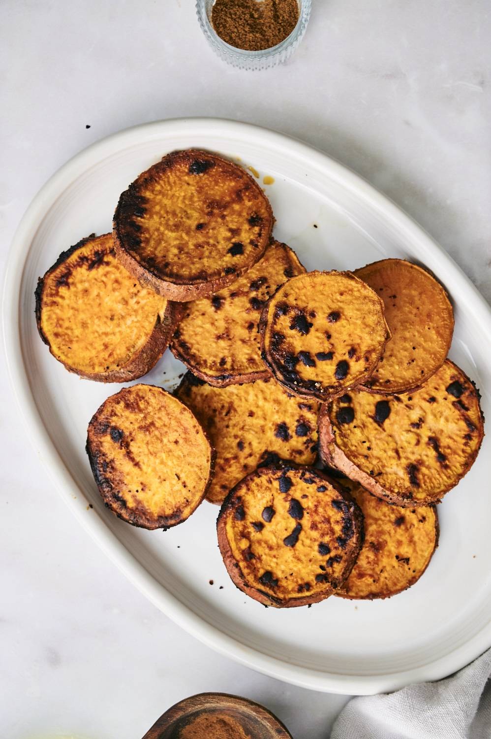 Sweet potatoes that were cooked on the grill served on a white platter.