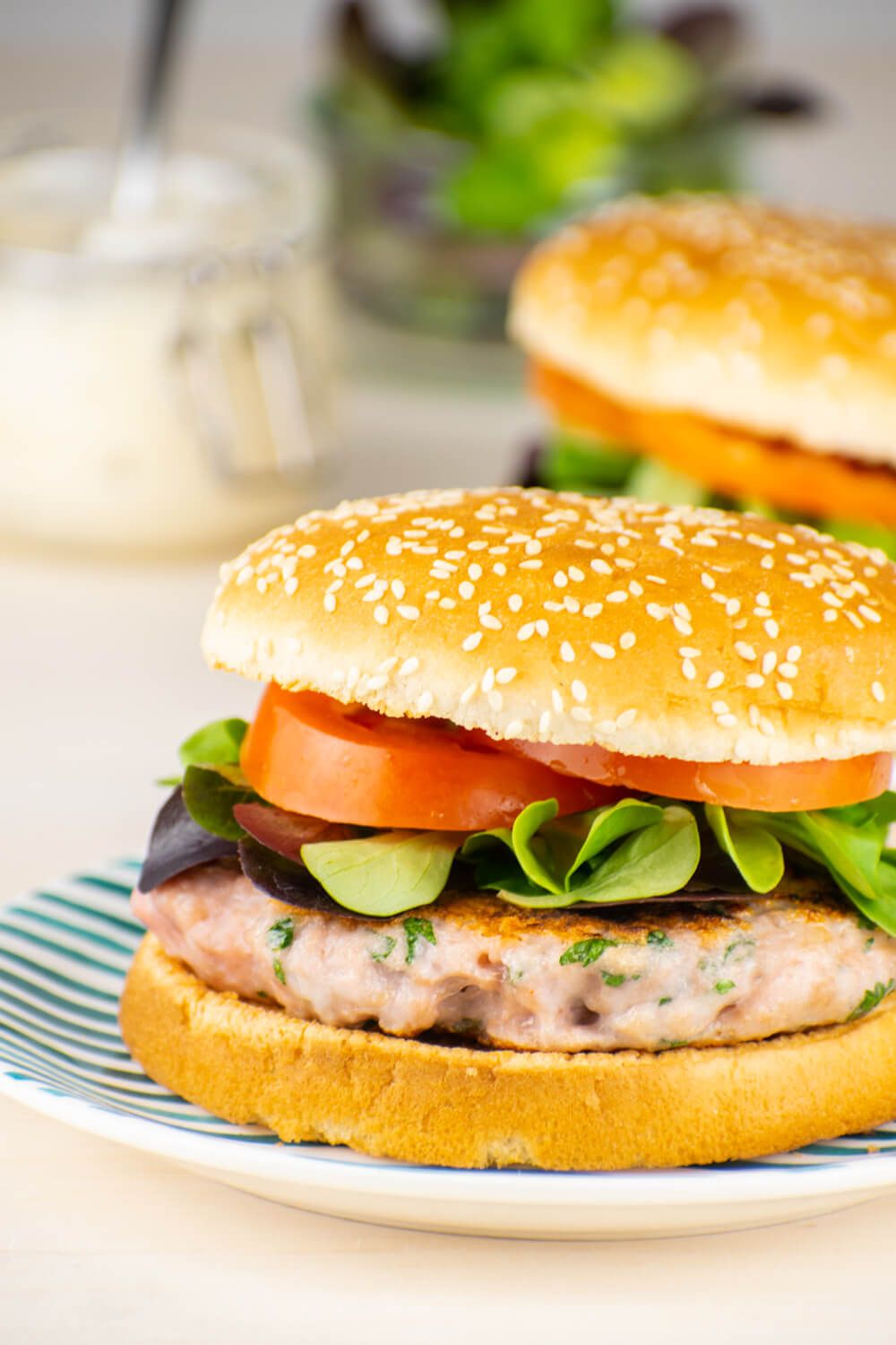 Caesar Chicken Burgers on a sesame seed bun with dressing, tomatoes, and lettuce.