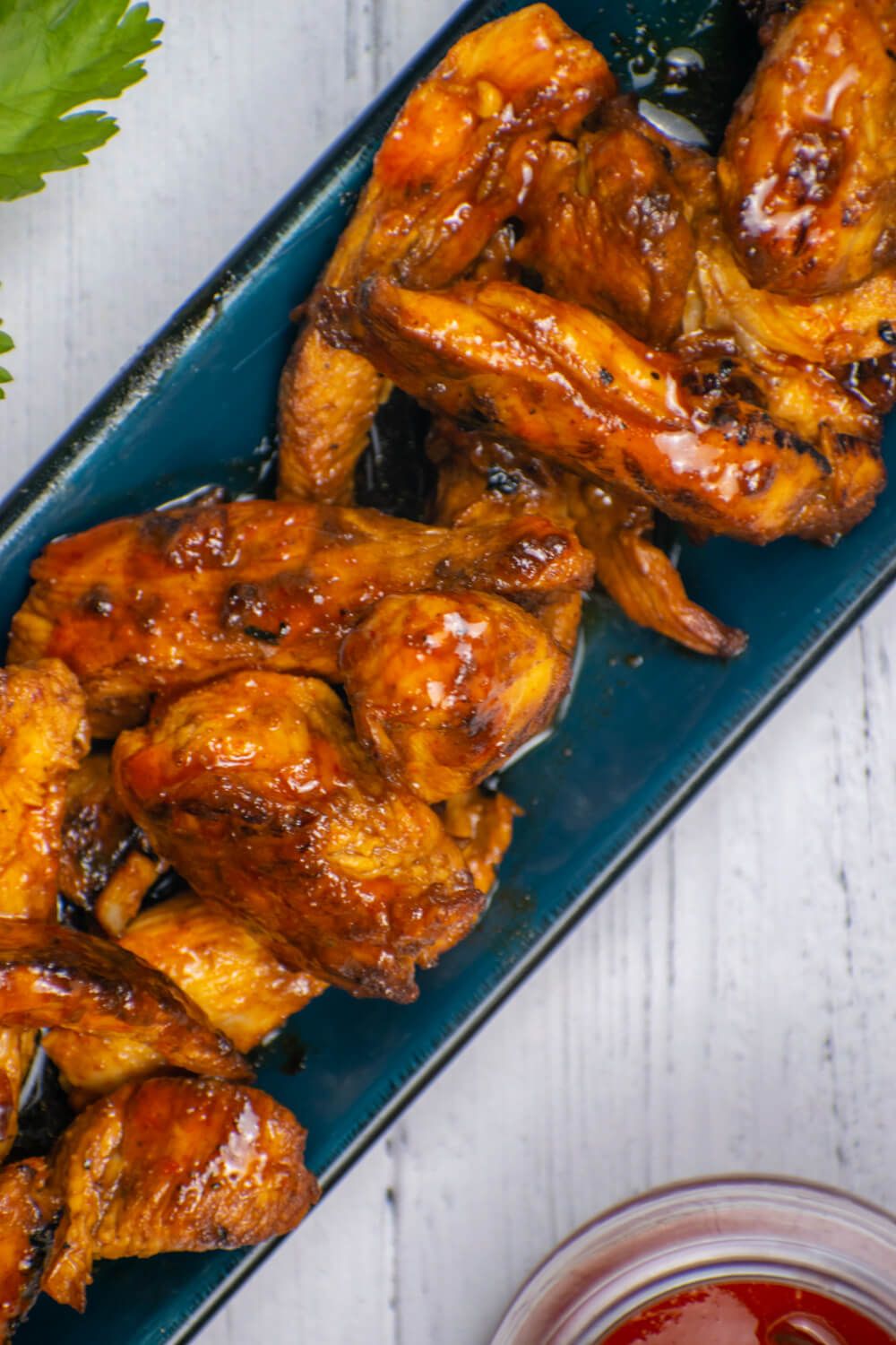 Sriracha honey chicken with an easy sauce on a plate with cilantro and Sriracha on the side.