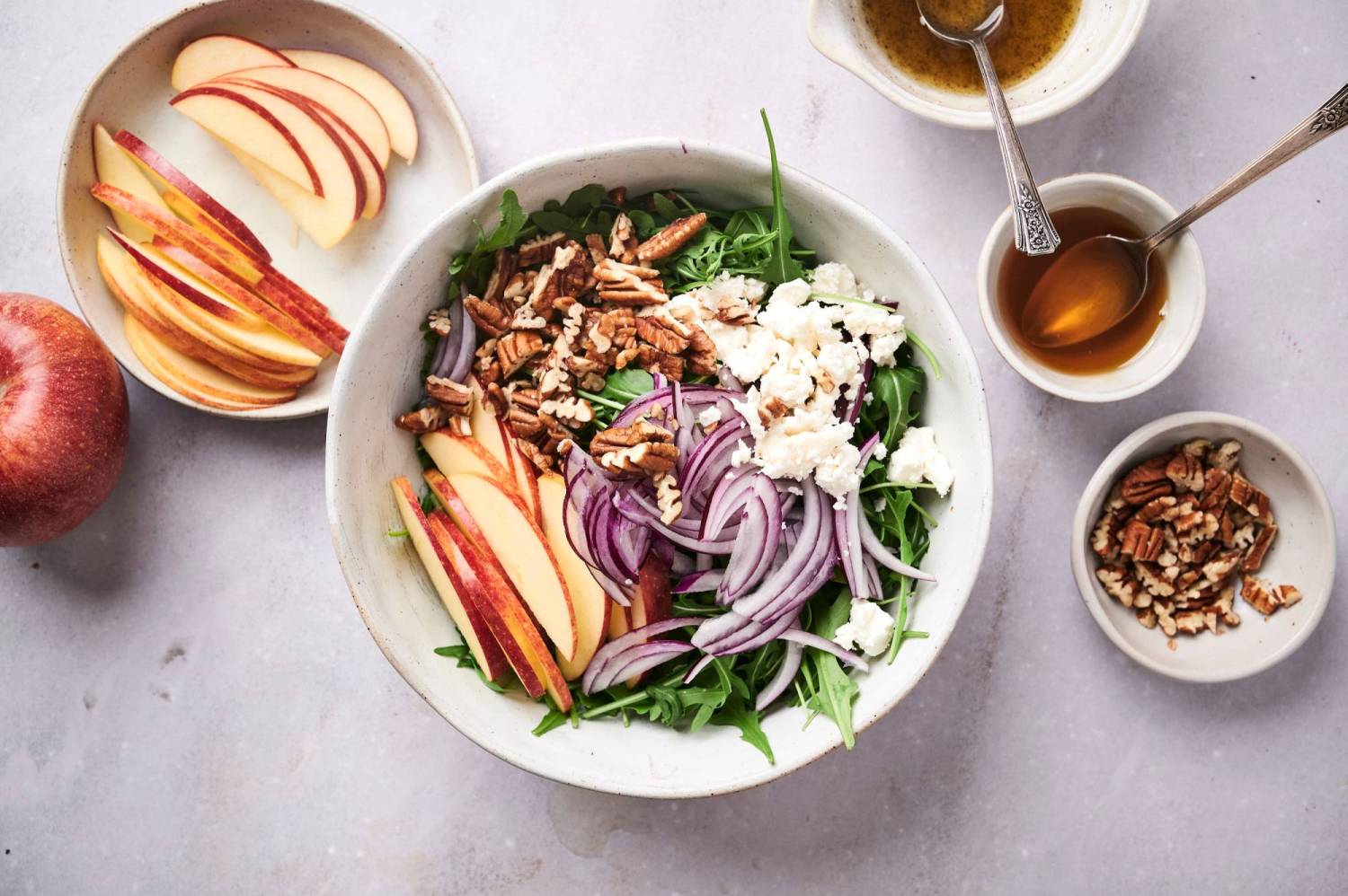 Arugula apple salad with pecans, goat cheese, red onions, and vinaigrette on the side.