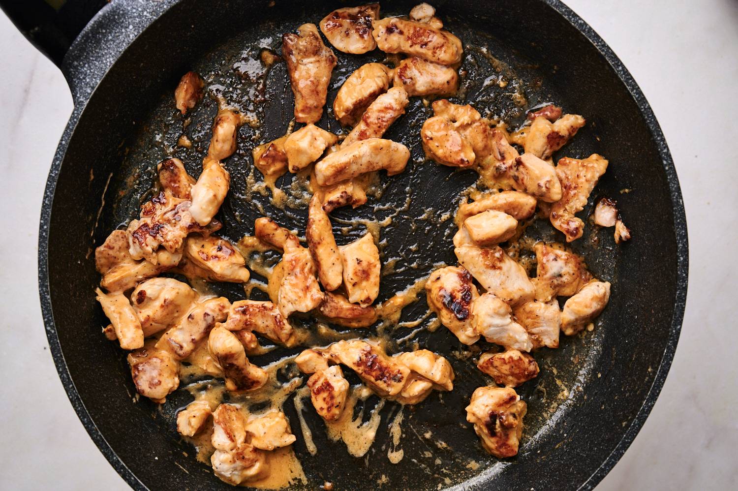 Chicken breast with bang bang sauce in a heavy cast iron skillet.