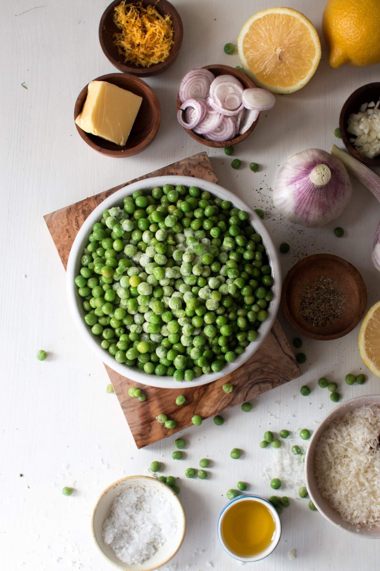 Sauteed pea ingredients including frozen peas, garlic, shallots, butter, and Parmesan cheese.