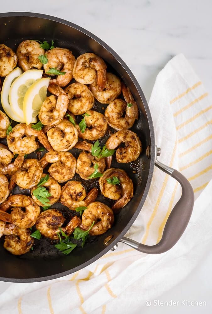 Shrimp in cajun seasoning cooked in a pan with lemon and parsley.