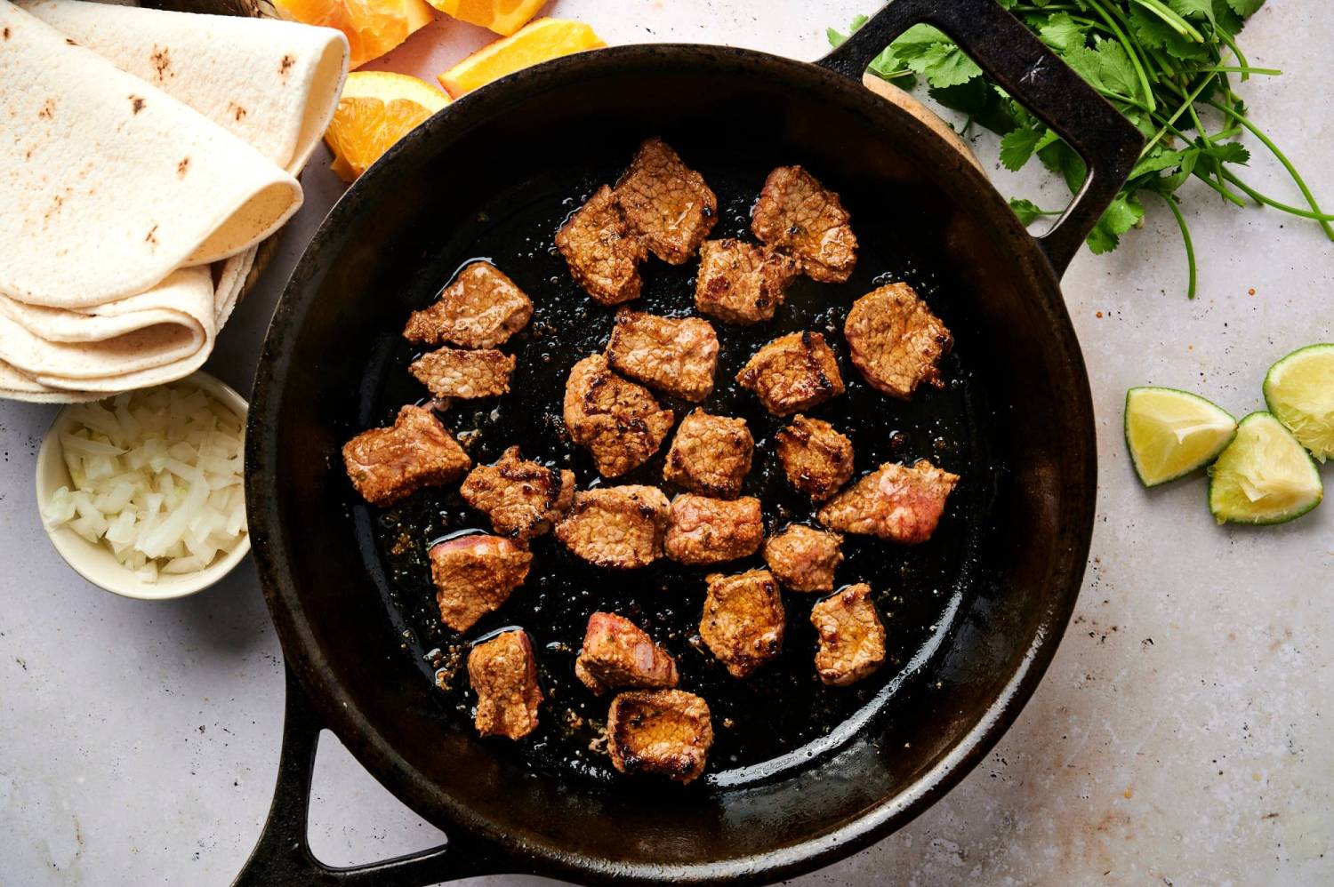 Carne asada cooking in a hot cast iron skillet for street tacos. 