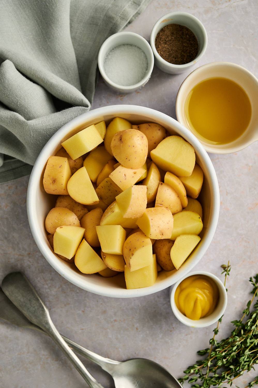 Ingredients to make easy roasted potatoes including mustard, olive oil, baby potatoes, salt, and pepper.