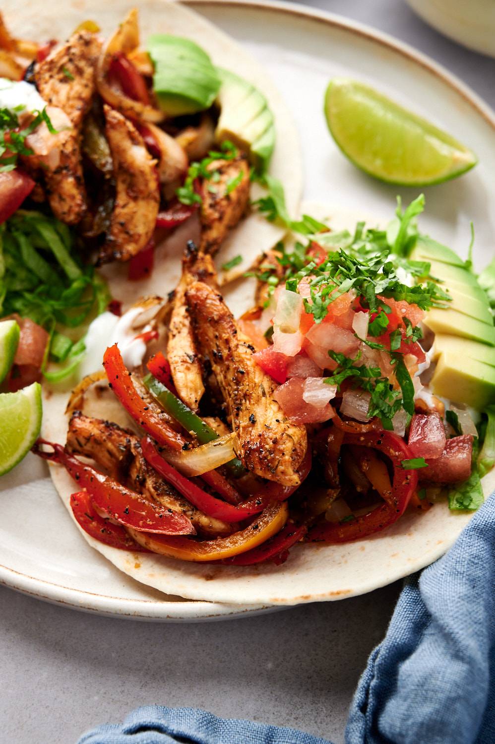 Tacos with chicken fajita filling served on corn tortillas with avocado, sour cream, lettuce, and pico de gallo.