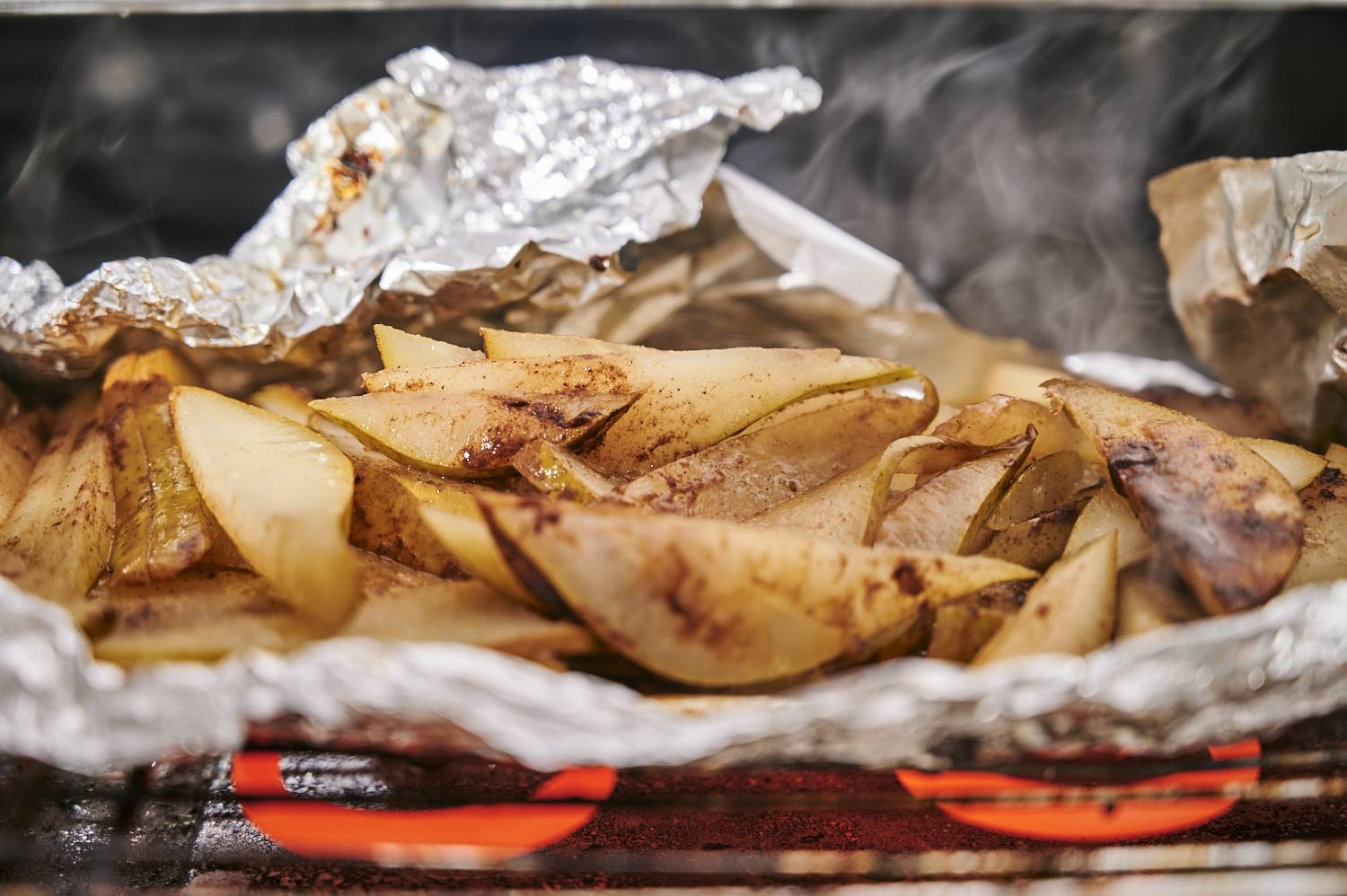 Sliced pears in a foil packet cooking on the grill with cinnamon and sugar.