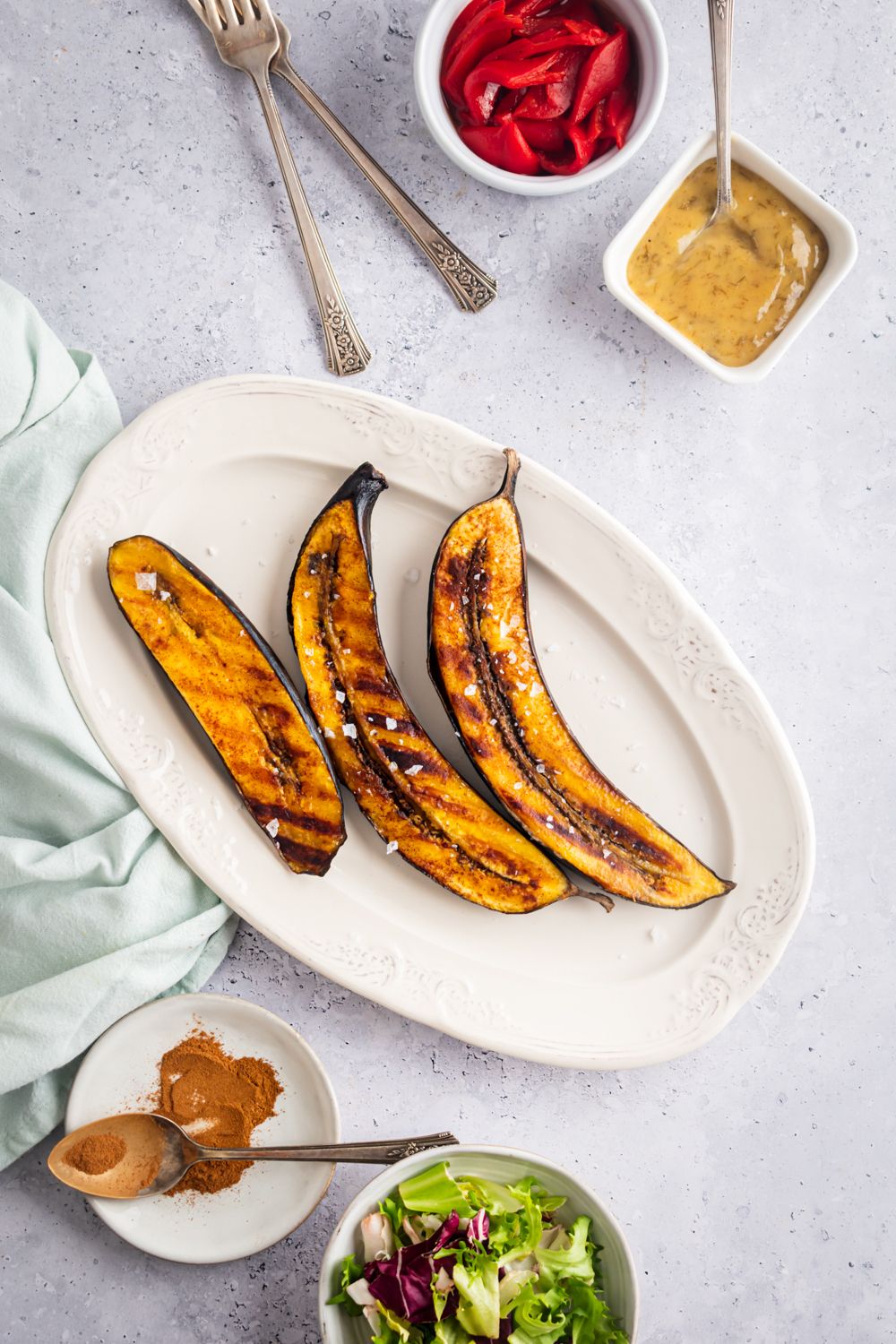 Plantains that are grilled with cinnamon and coconut oil on a white plate.