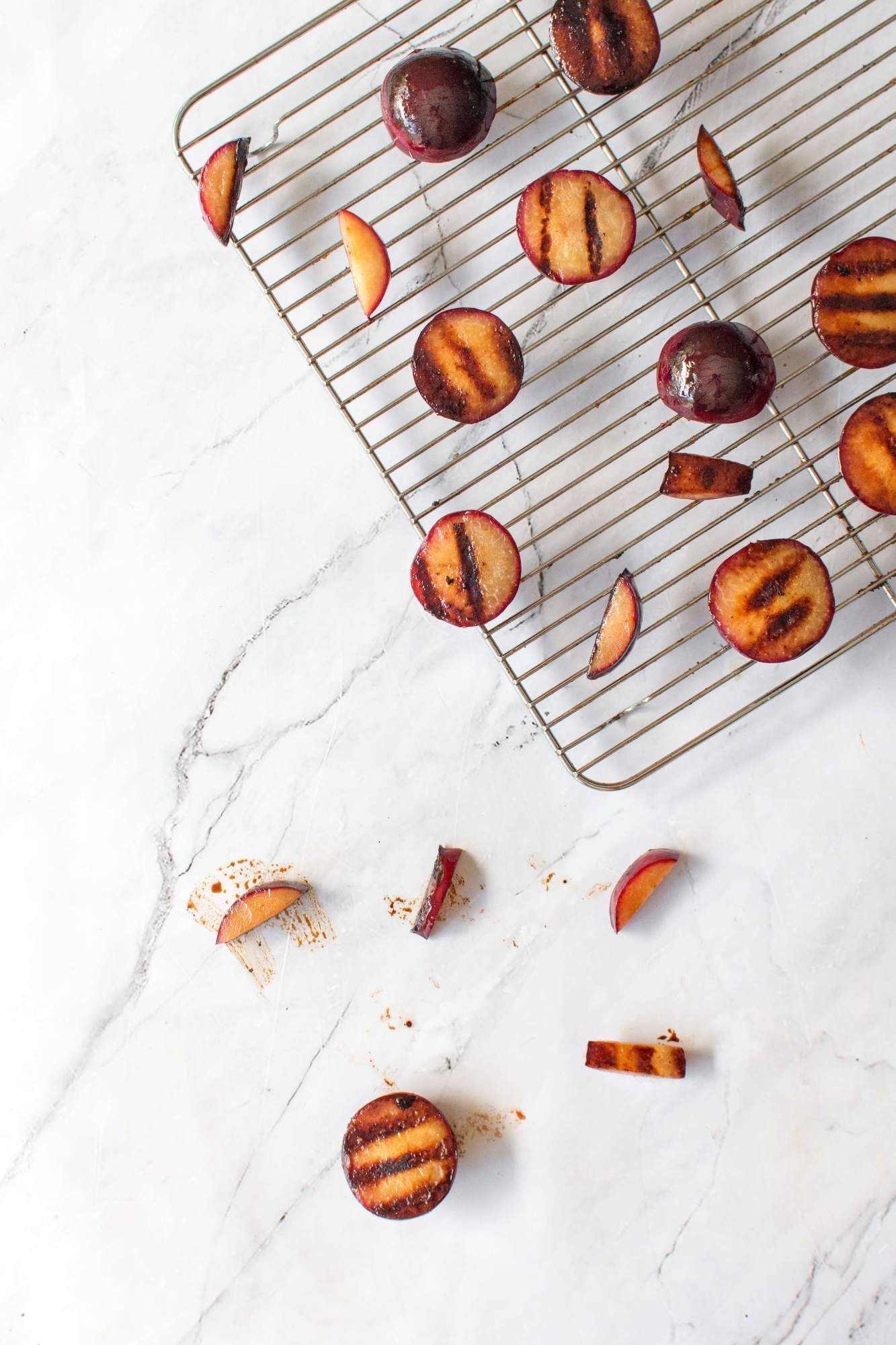 Grilling plums with grill marks on a wire rack.