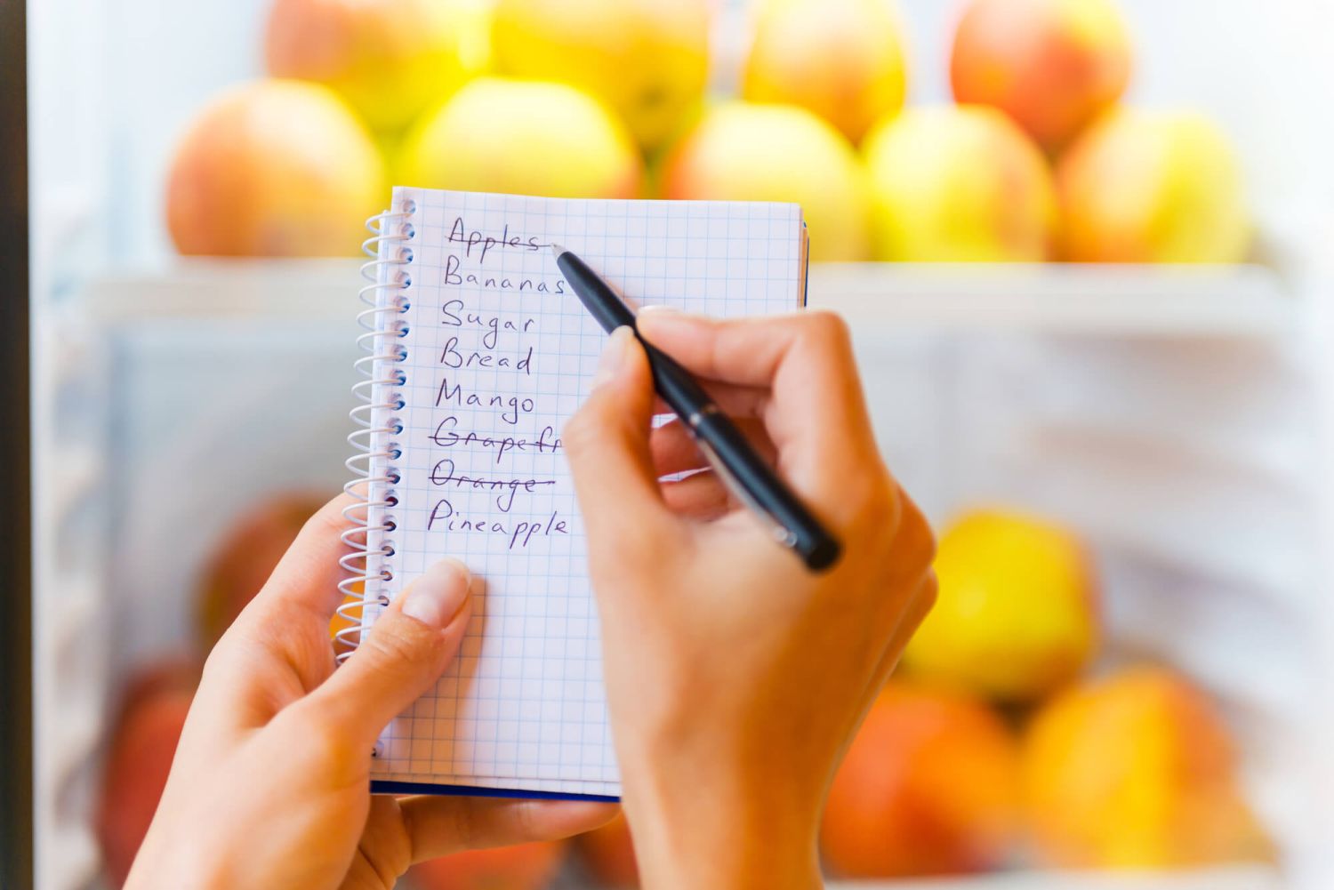 Shopping list with pencil and fridge in the background.