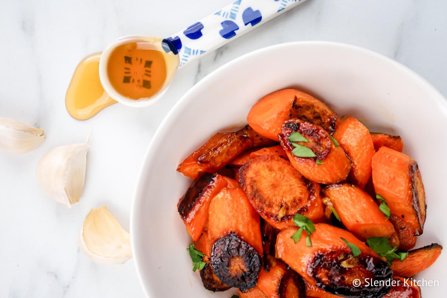 Roasted carrots with honey and garlic in a bowl with fresh parsley.