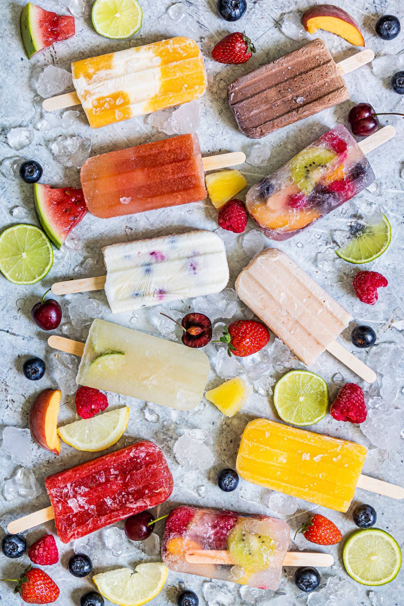 Various popsicles including fruit flavors, chocolate, and creamy pops with ice and fresh fruit.