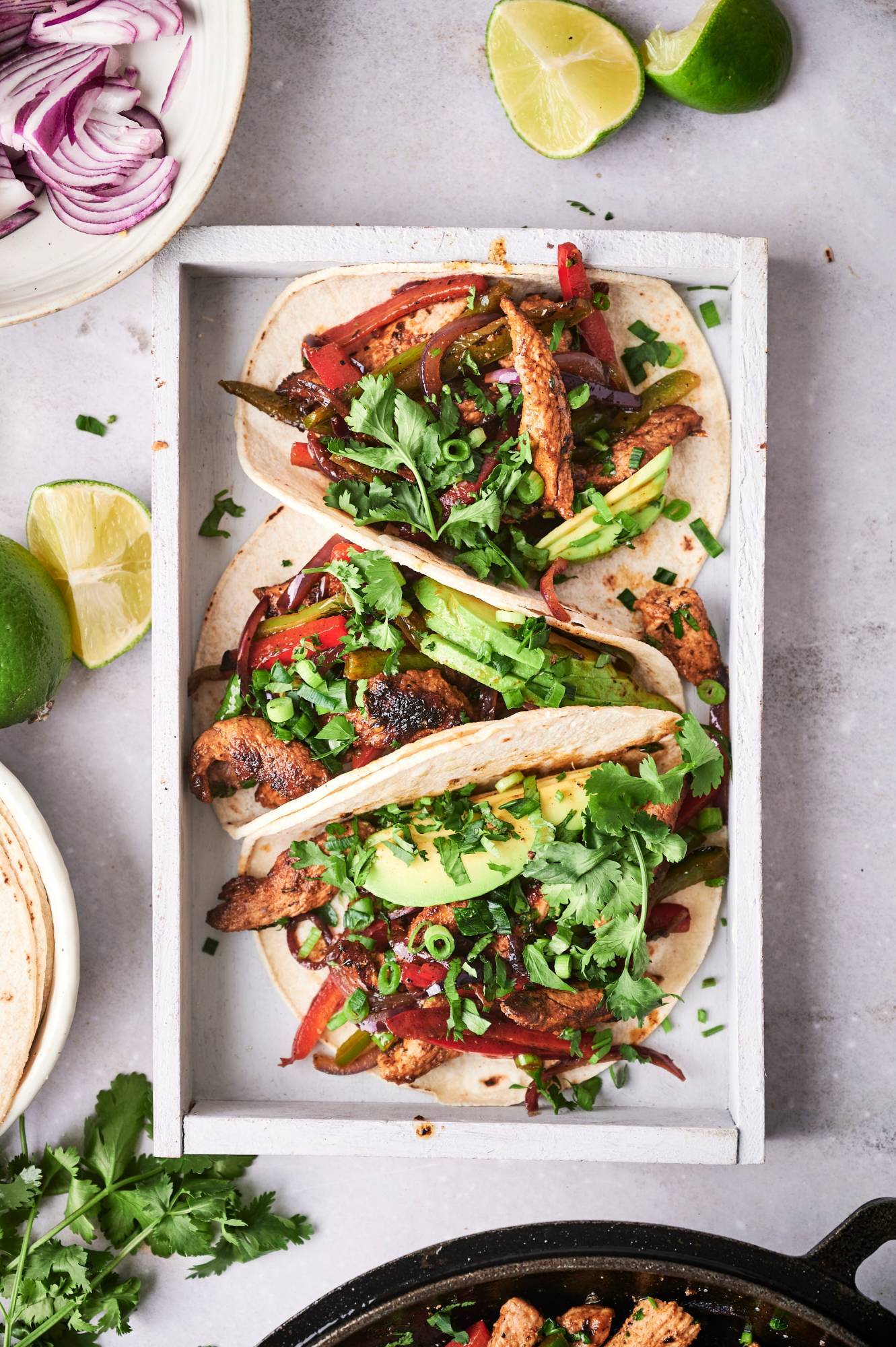 Fajitas made with pork tenderloin, bell peppers, and red onion served in corn tortillas with avocado and cilantro.