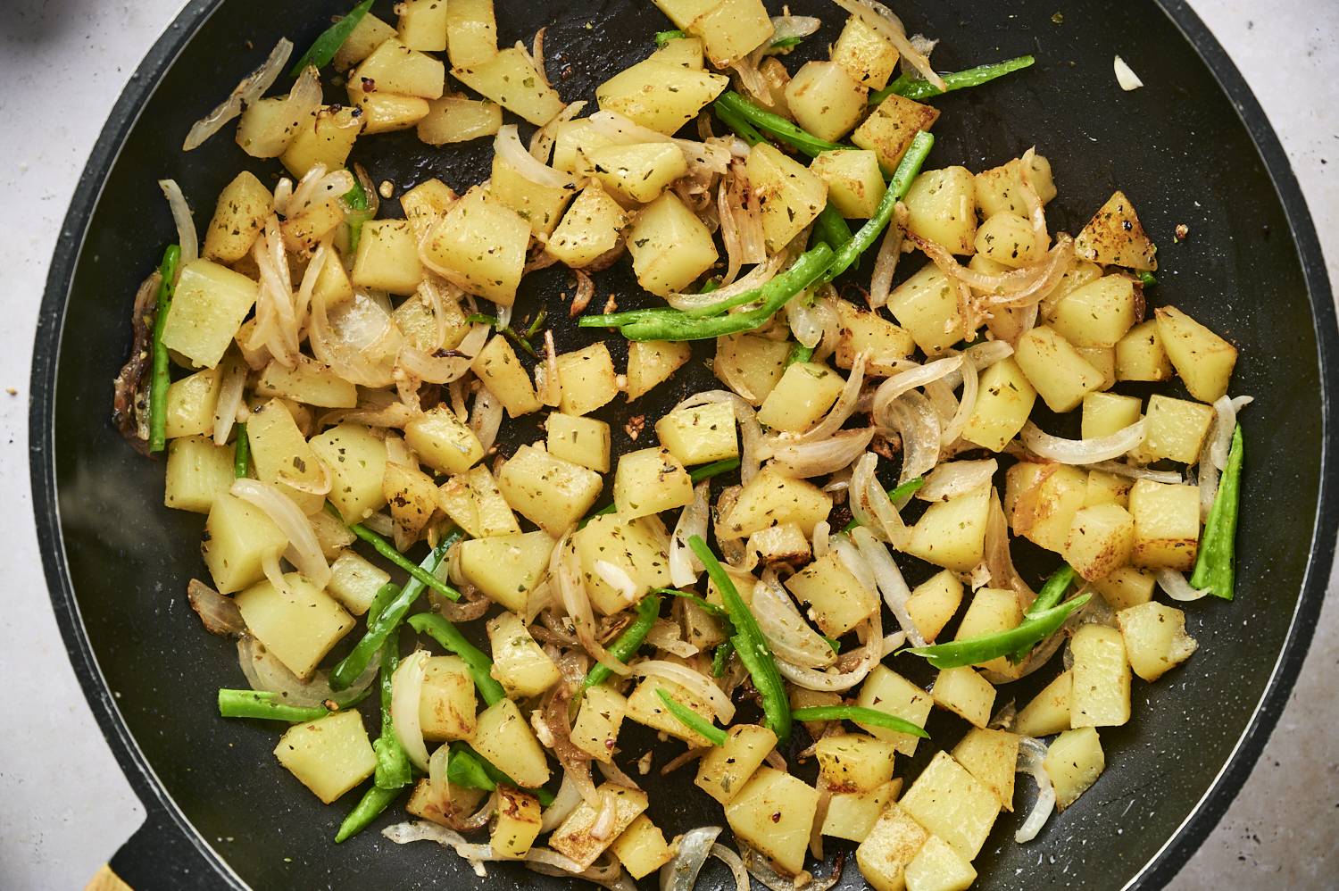 Sauteed potatoes with green chiles and onions in a skillet for making potato tacos.