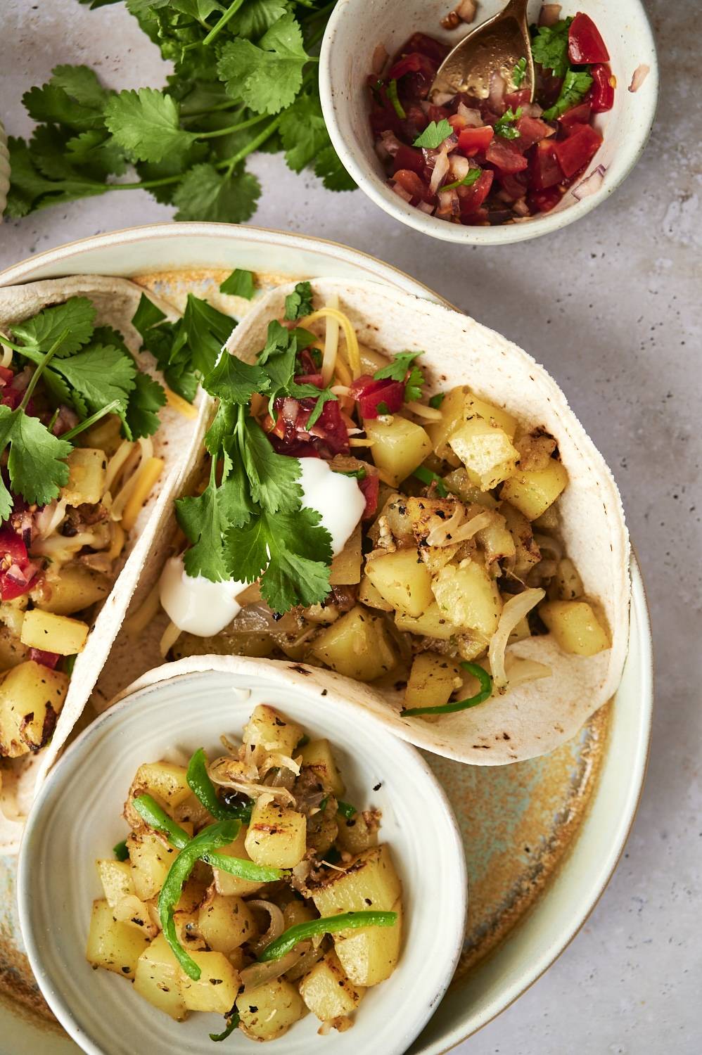 Potato tacos with onions, poblano peppers, sour cream, pico de gallo, and cilantro served in corn tortillas. 