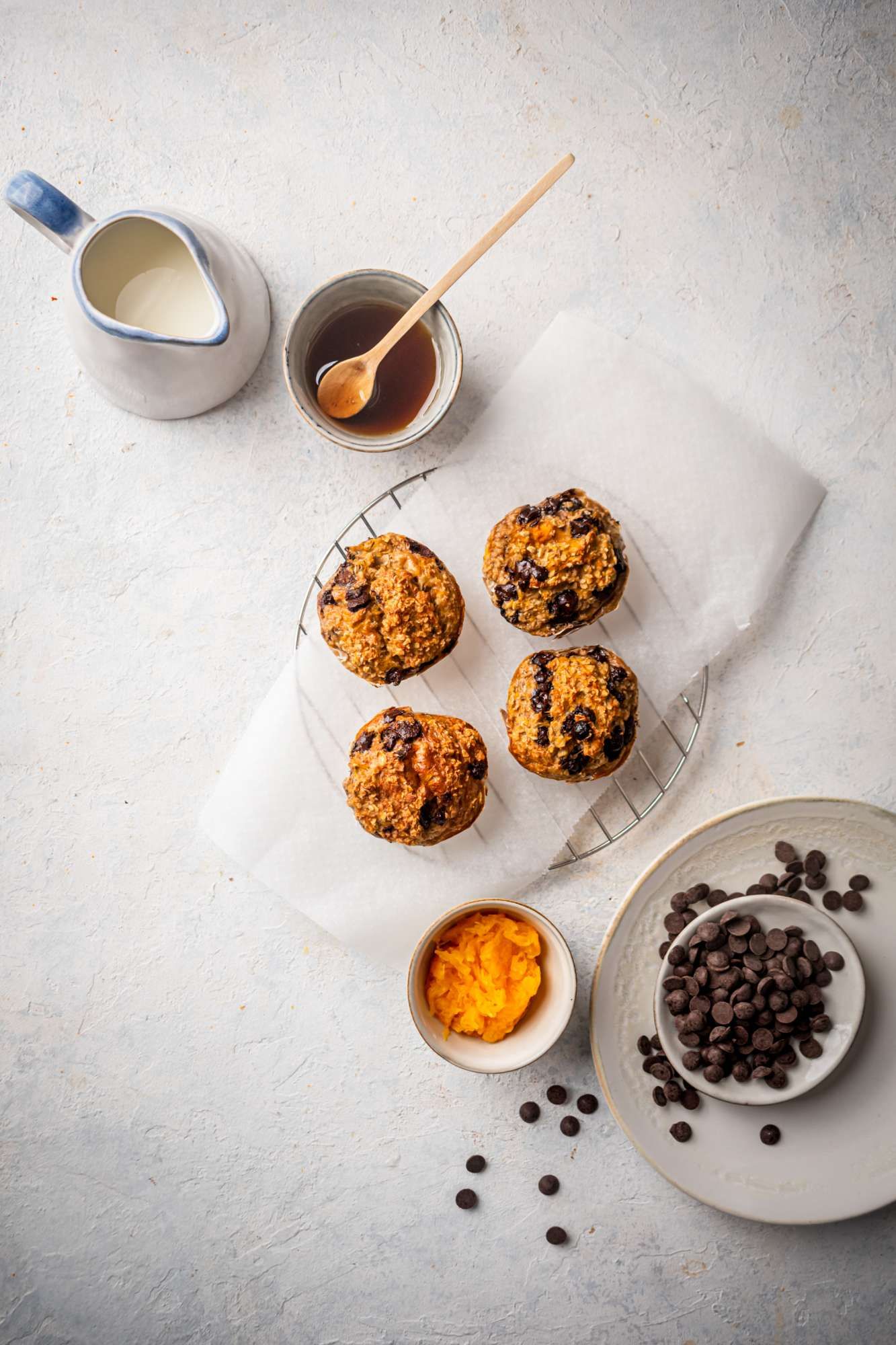 Pumpkin muffins made with oatmeal and chocolate chips on a cutting board with maple syrup on the side.